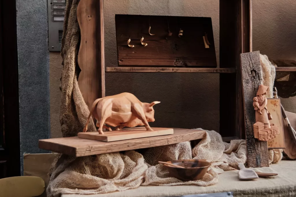 Sculptures sur bois exposées à la Foire de Saint-Ours, à Aoste : un taureau, une statuette, des cuillères